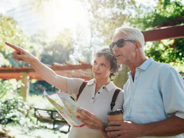 Couple of senior tourists using a city guide searching locations and pointing